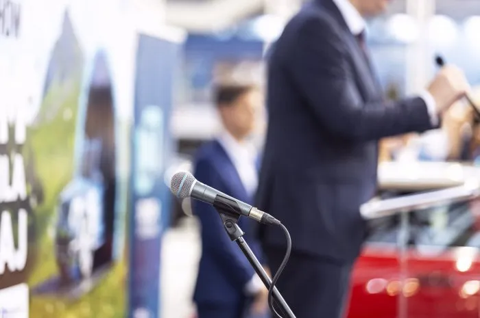 public speaking or relations with copy space concept microphone in focus, blurred unrecognizable person in the background