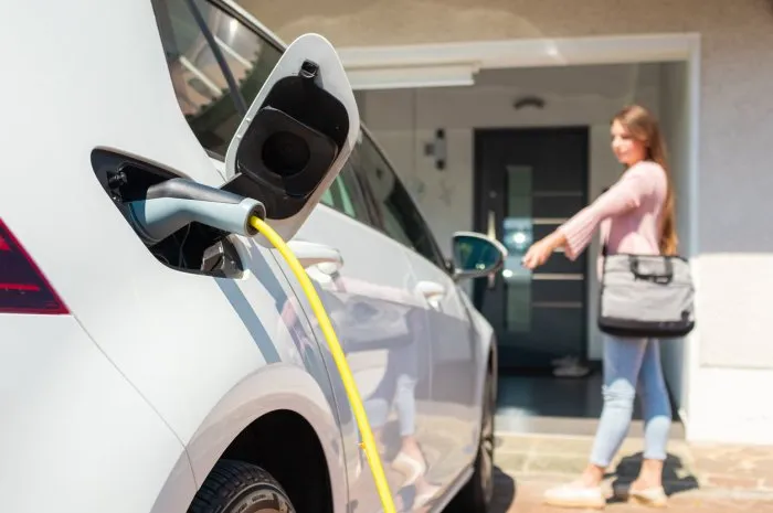 woman charging electric car at home with cable