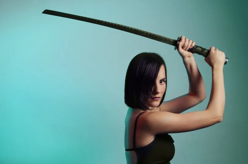 mystic beautiful black hair girl with sword, copy space on teal background