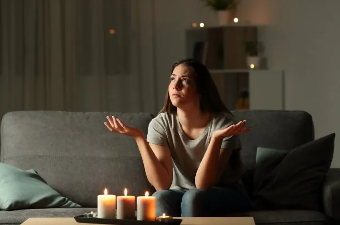 woman complaining during a blackout sitting on a couch in the living room at home