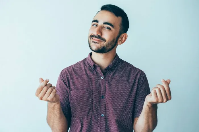 closeup portrait of content man looking at camera, showing money gesture and asking for money money concept isolated front view on white background