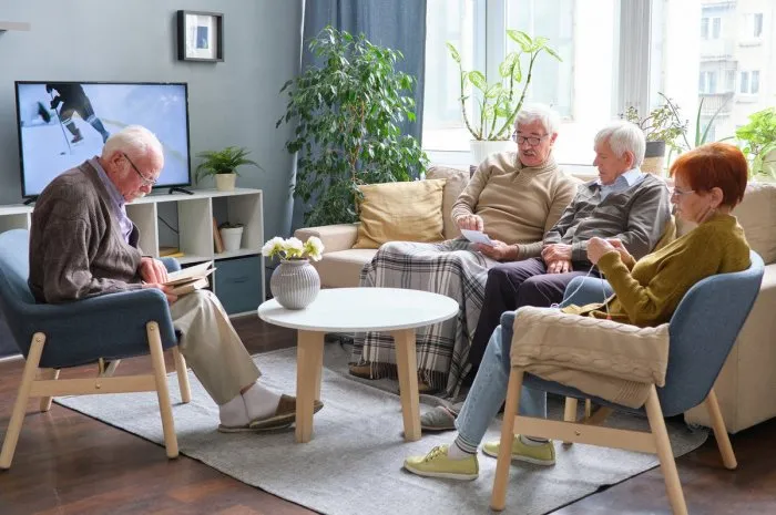 senior people reading a book, watching tv and talking to each other during their leisure time in nursing home