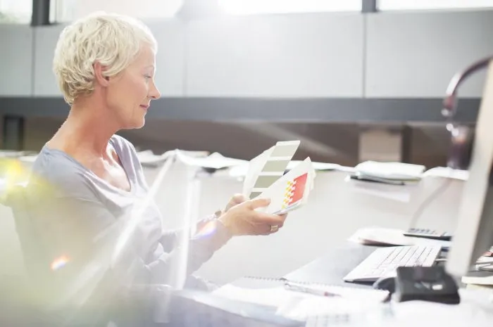 businesswoman examining paint swatches at office desk