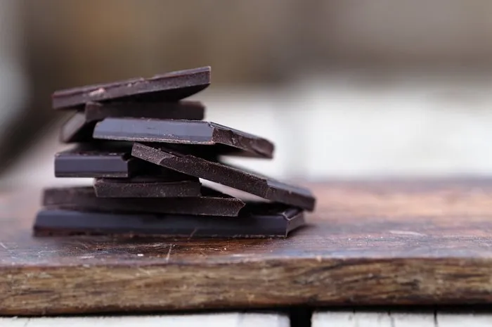 stack of broken dark chocolate bar pieces on a wooden background horizontal