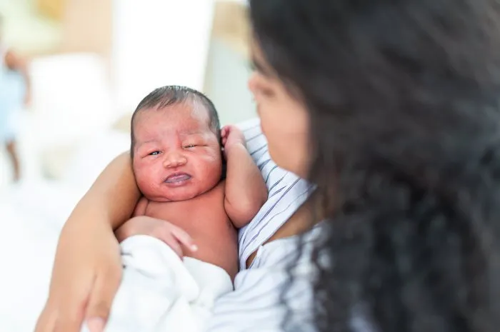 african american mom carrying of her newborn baby at home happy mum holding infant child on her hands mother hugging her newborn baby on bed family, happy, love and new life concept