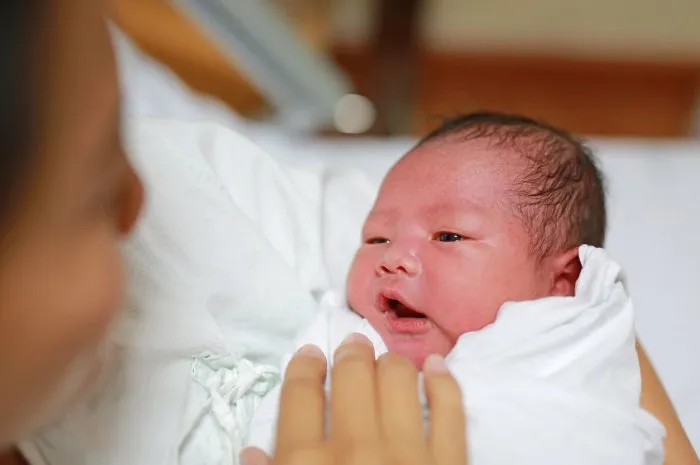 asian mother carrying her baby on her breast