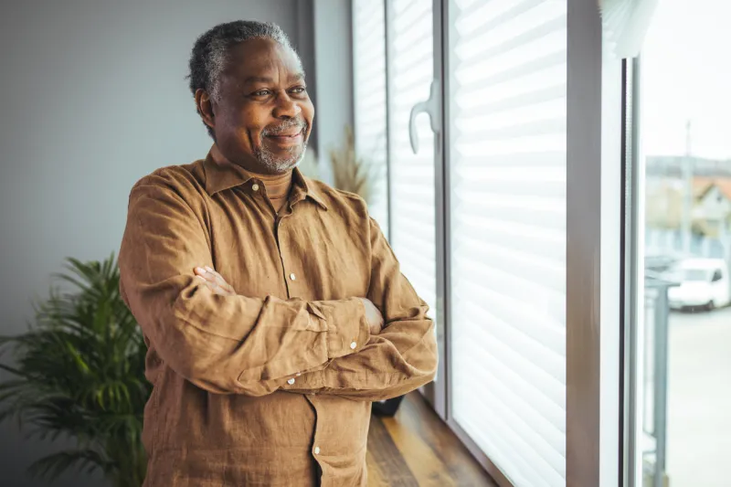 portrait of smiling senior african american man at home near window portrait of happy senior man at home happy mature african american man smiling