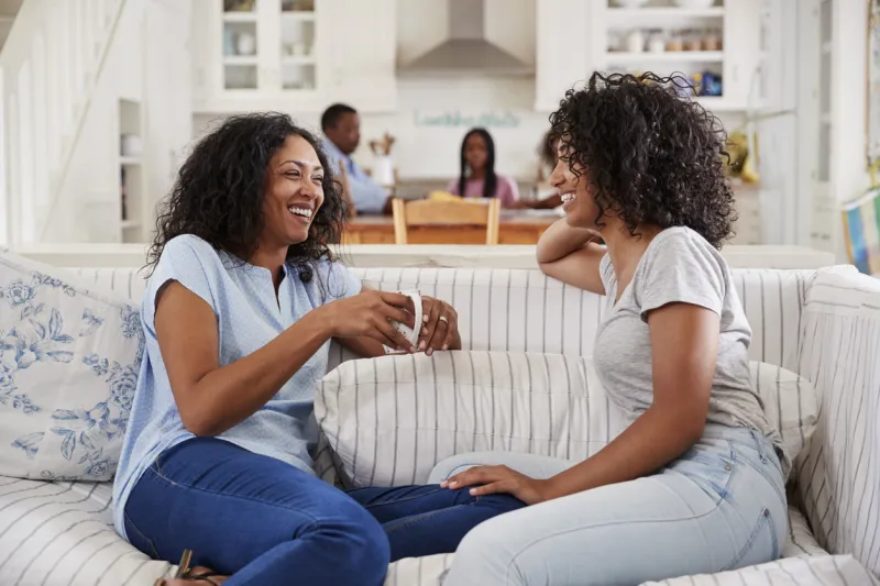 mother talking with teenage daughter on sofa