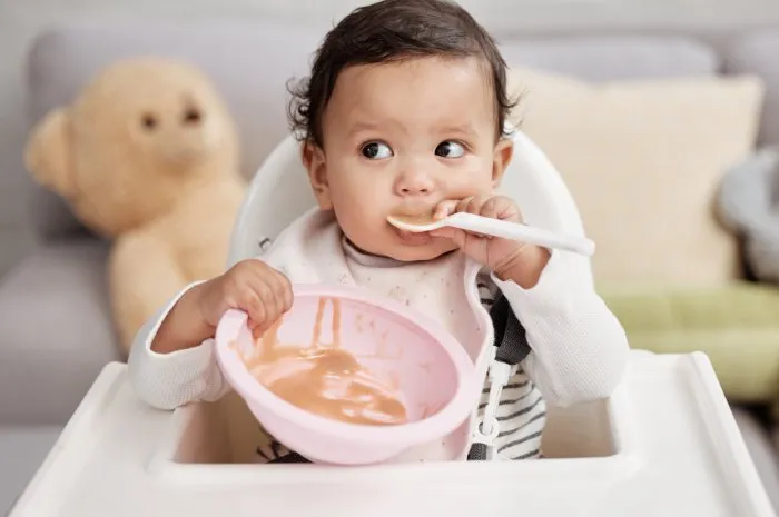 shot of a baby eating a meal at home