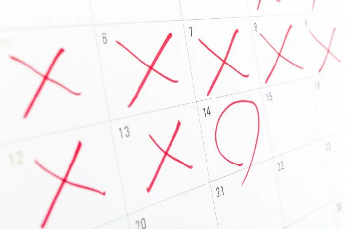 close up of a white calendar page with some of the days crossed off with a red x