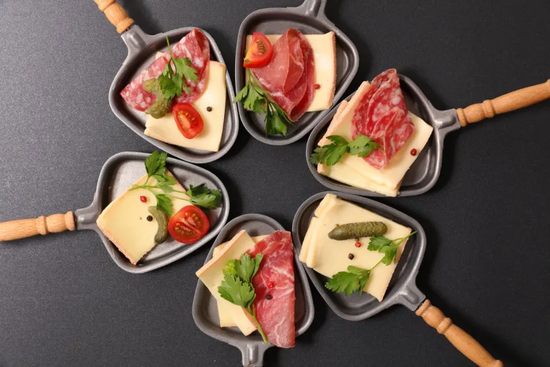 assorted of spoon with cheese raclette, salami and tomato