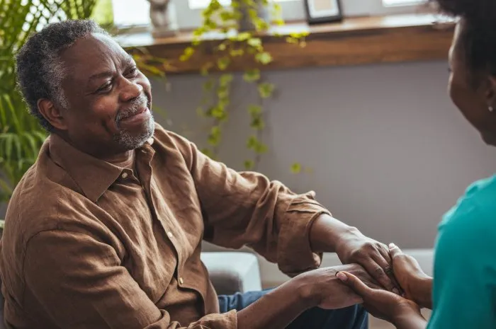 female healthcare worker holding hands of senior man at care home, focus on hands doctor helping old patient with alzheimer's disease female carer holding hands of senior man