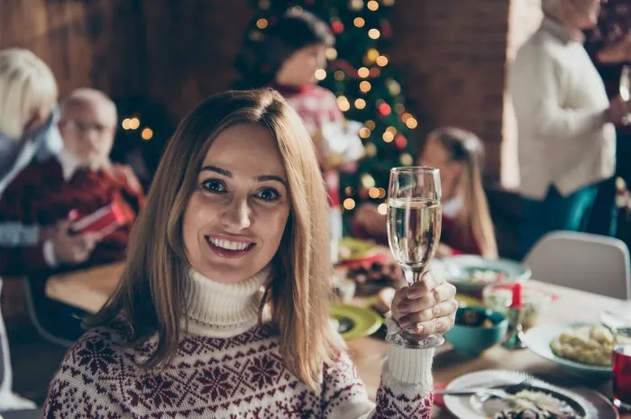 portrait of cheerful girl with glass of wine noel morning gathering, meeting, tradition grey-haired grandparents, grandchildren, relatives, sister, brother, son, daughter at house feast lunch table