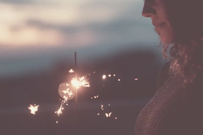 sparkler light day dreaming celebration concept emotion and activity with side view of happy woman smiling and celebrating alone in the evening colorful dusk background people celebrating alone