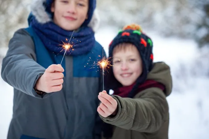 happy family two brothers keep a sparklers or bengal fires outdoor in beautiful winter forest winter holiday concept