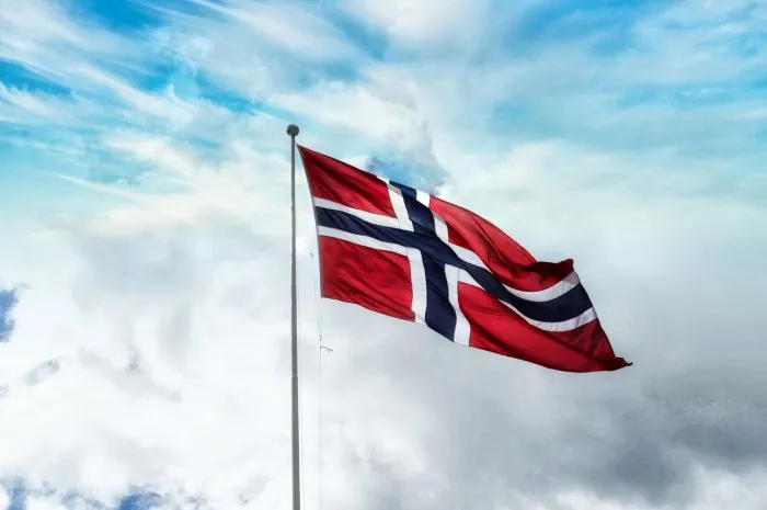 norwegian flag waving high against blue sky with dramatic clouds symbol for patriotism and nationality