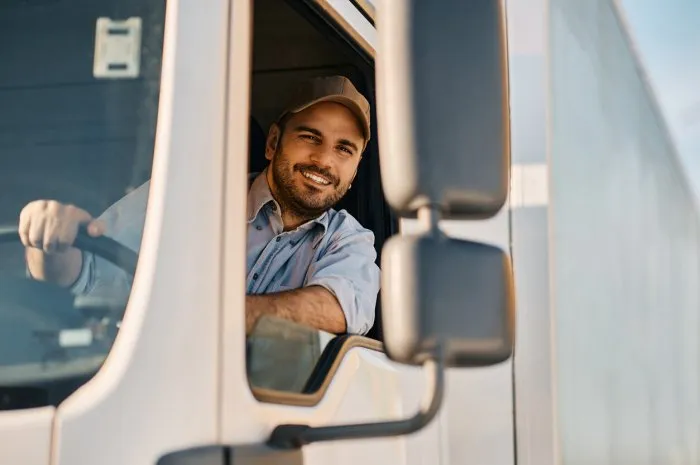 happy professional truck driver driving his truck and looking at camera copy space