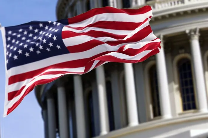 the flag of the united states of america flying in front of the capitol building blurred in the background united states federal congress on capitol hill in washington dc democracy and freedom