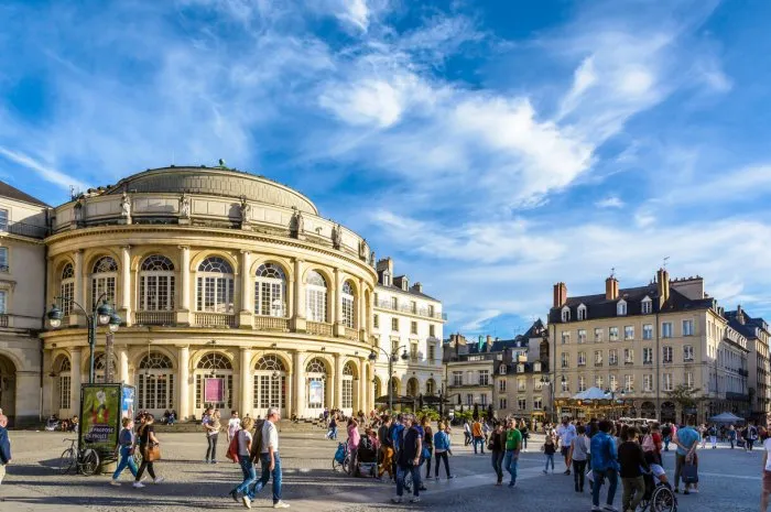 rennes, france - october 13, 2018  people strolling on the pedestrian town hall square in front of the rounded facade of the opera house by a sunny saturday afternoon under a deep blue sky