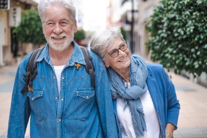 happy active smiling adult caucasian senior couple walking in the city holding hands as tourists attractive white-haired people dressed in denim enjoying freedom, retirement, vacation and travel