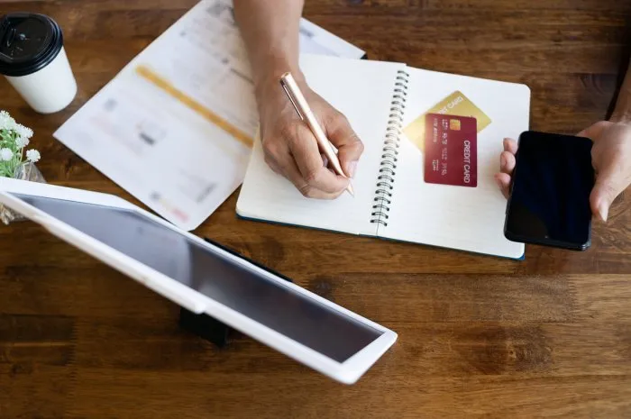 male hand calculating his monthly expenses with credit card,smart phone and digital tablet, concept for shopping online,payment , top view