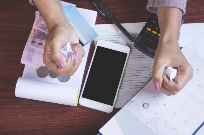 deadline calendar, smart phone,money,credit card,calculator and saving account on table with blur background of angry business woman hand crumpling paper, debt,payment concept