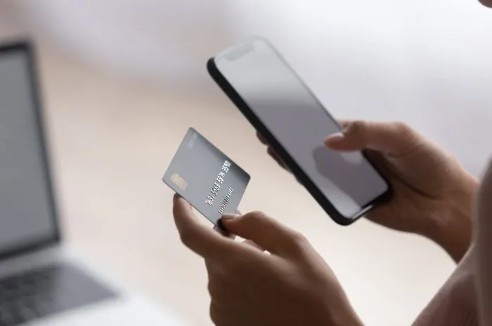 female hands holding plastic card and cellphone purchasing goods online e-bank apps, financial e-services, spend money using modern technology, e-commerce shopper, secure electronic payment concept