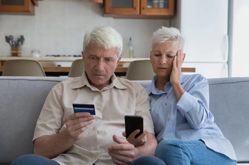shocked aged couple become victims of online fraud using credit card phone to pay for goods order service online on suspicious website frustrated older spouses overspending money at internet shopping
