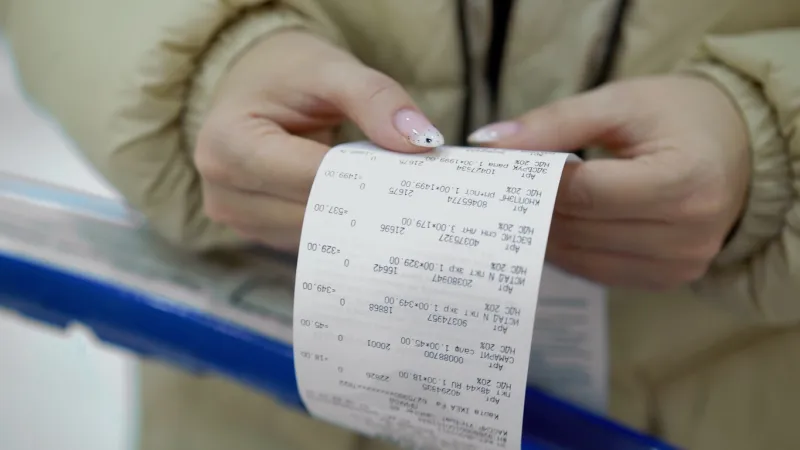 the buyer holds a purchase receipt in his hands, checks purchases and prices woman in a supermarket with a shopping cart girl with paper bill in store