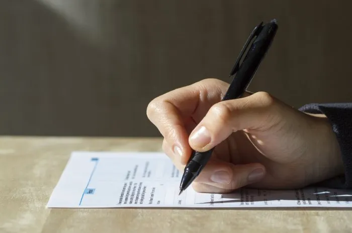 closeup of woman's hand holding a pen filling out a census form