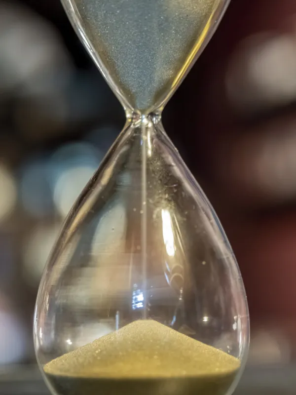 sand timer hourglass in operation selective focus on the fine grains of golden sand apex below