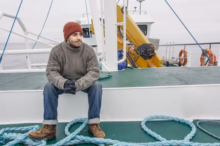 lone fisherman sitting on bench at the commercial ship