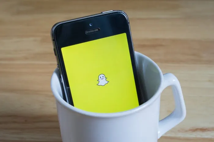 bangkok, thailand - april 22, 2017   apple iphone5s in a mug showing its screen with snapchat logo