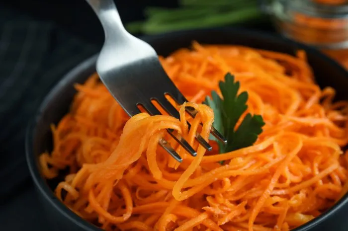 fork with korean carrot salad over bowl, closeup