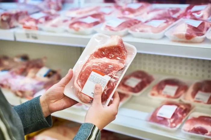 buyer hands with pork meat packages at the grocery store