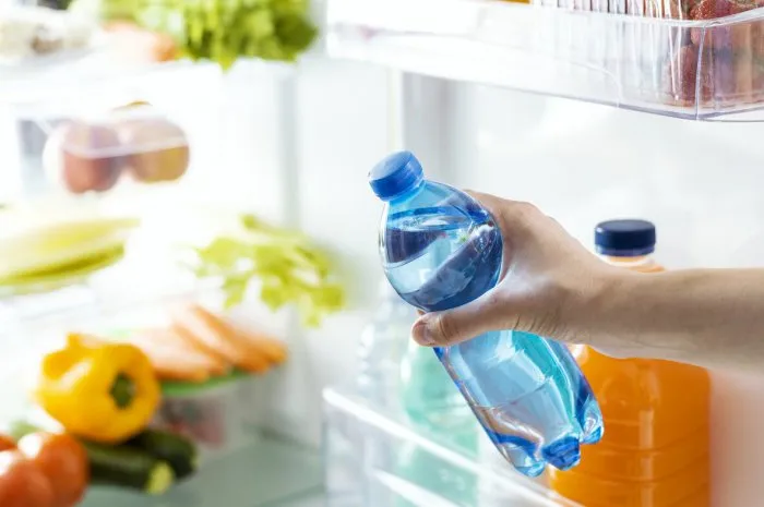 woman taking a bottle of fresh water from the fridge, beverage and hydration concept