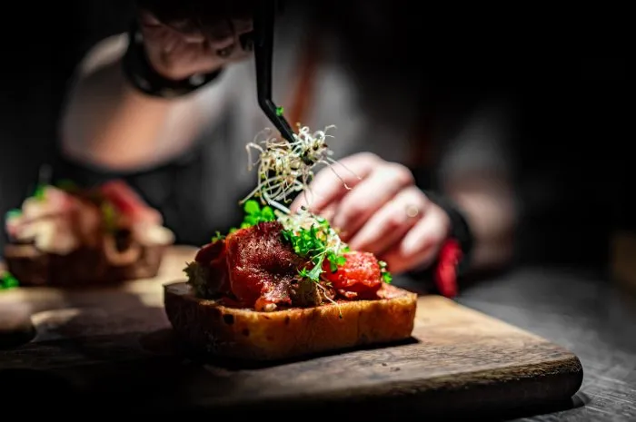chef hand decorate food on wooden plate in cafe kitchen