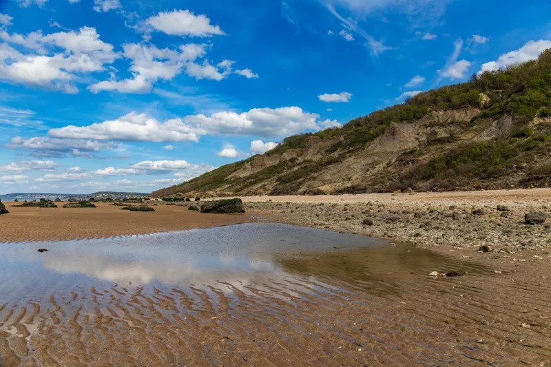 villers-sur-mer, normandy, france - rocks on the beach at low tide near the black cows (vaches noires) cliff