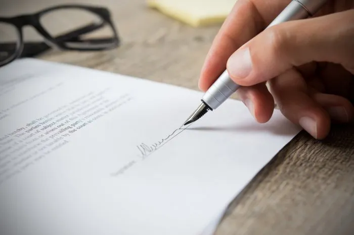 close up of hand of businessman signing a form business man signing contract for future deal business man signing legal document male hand signing employee contract with a bond