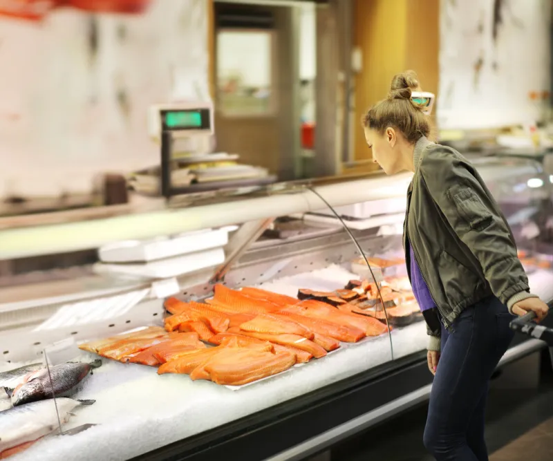 woman shopping for fresh fish seafood in supermarket retail store