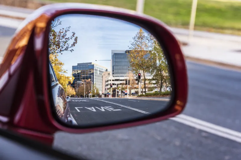 beautiful modern city skyline from rear view mirror at dusk, canberra, australia