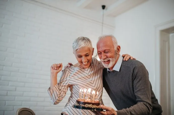mature couple celebrating holding a birthday cake