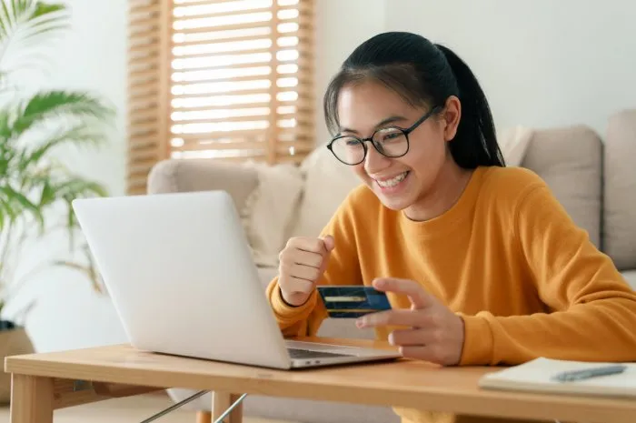 beautiful young woman are buying online with a credit card while sitting in the living room morning women are using a computer laptop and doing online transactions at home