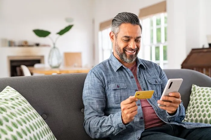 mixed race man paying online on mobile phone