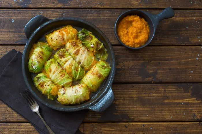 cabbage rolls stuffing with rice and vegetables serving in black cooking tray on bark wooden table flat lay copy space