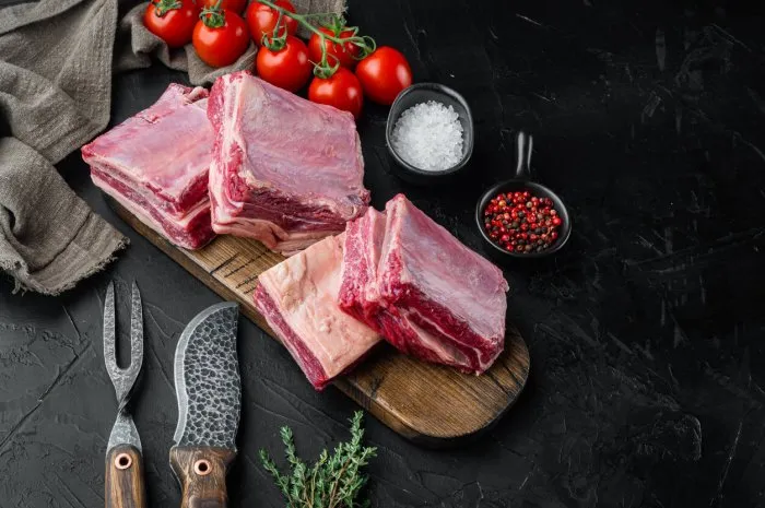 raw beef short rib set, with ingredients, on black stone background, with copy space for text