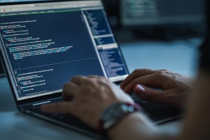 close-up focus on person's hands typing on the desktop computer keyboard screens show coding language user interface software engineer create innovative e-commerce app program development