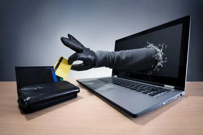 stealing a credit card through a laptop concept for computer hacker, network security and electronic banking security