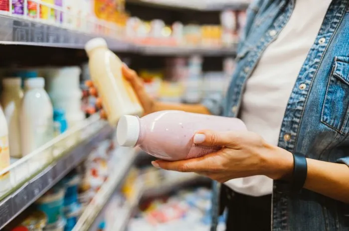 close-up of bottled dairy products in female hands at grocery store