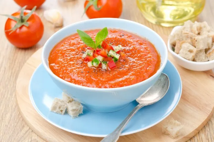 cold tomato soup gazpacho with basil and croutons in a blue bowl, horizontal